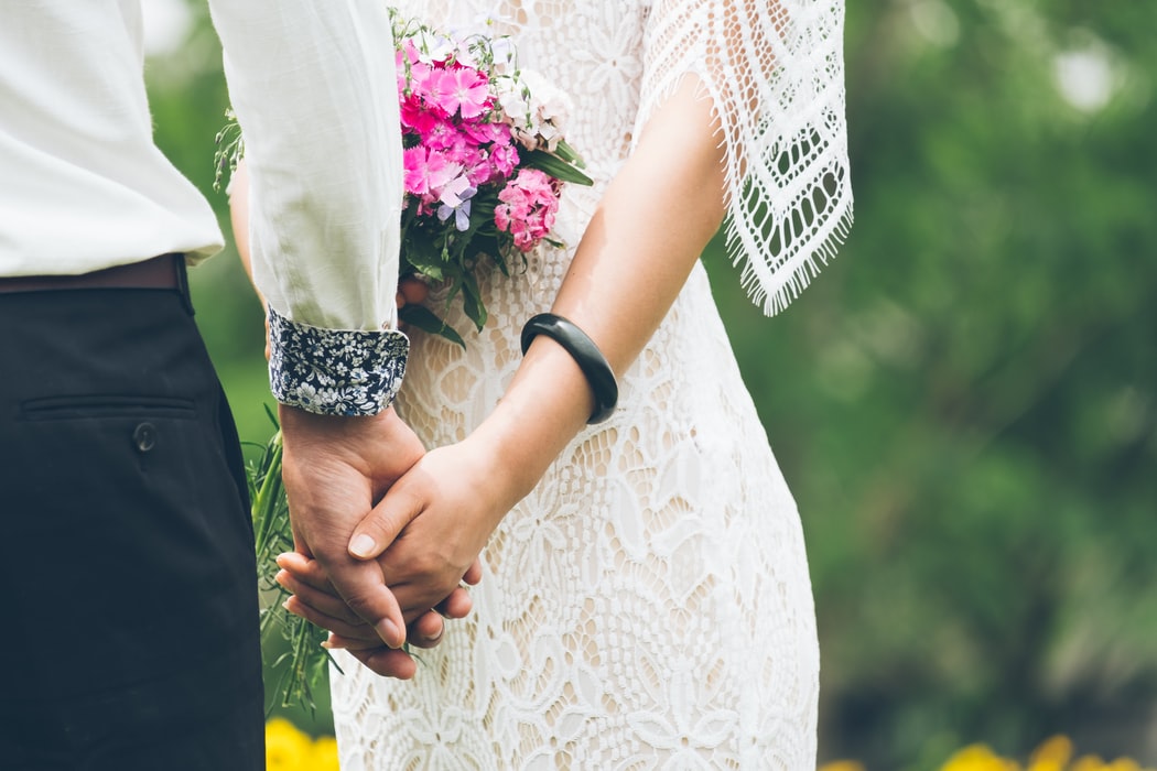 Et brudepar holder hender.